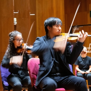 Young man playing violin in an orchestra