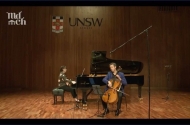 A woman playing a grand piano and a man to the right playing the cello